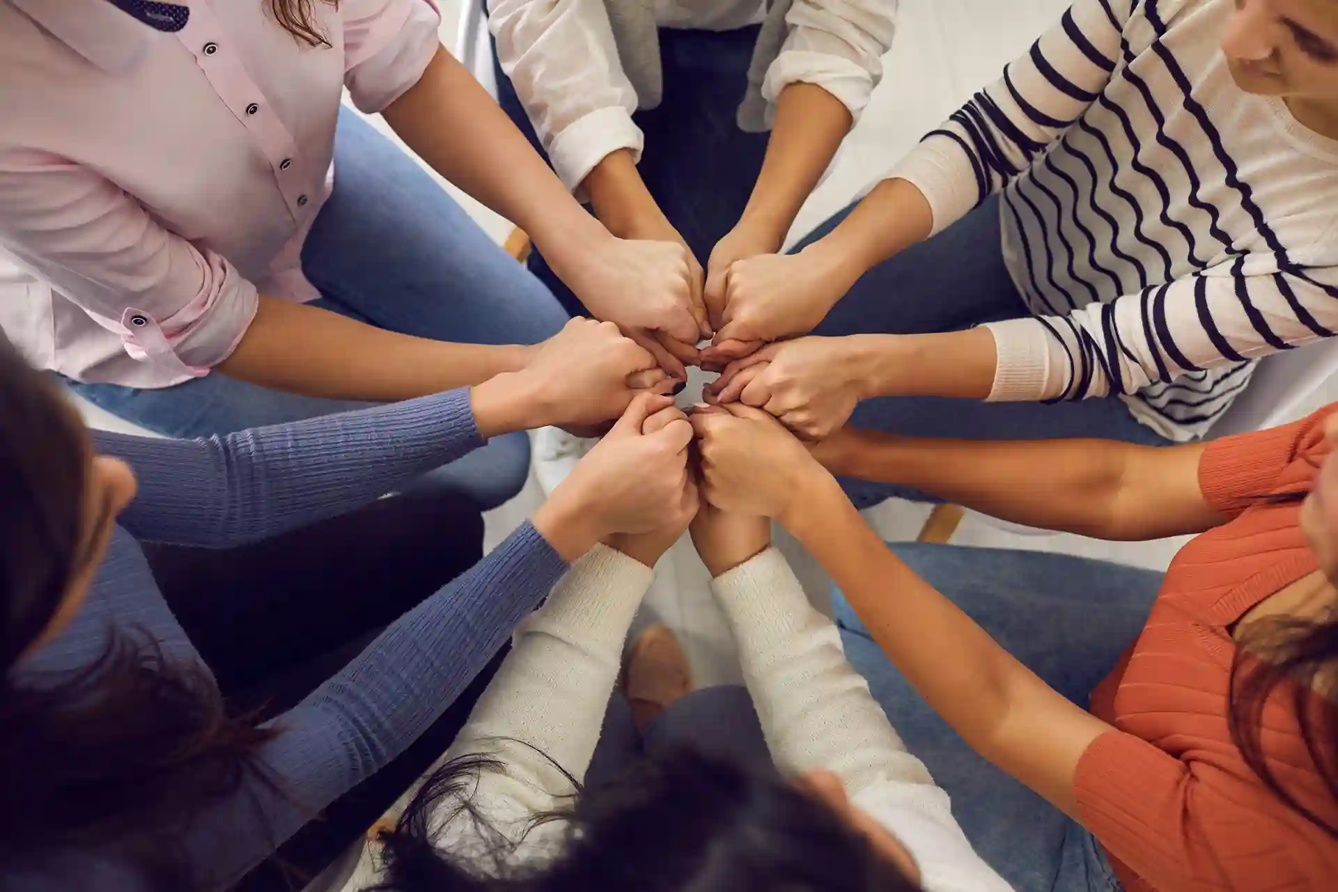 A group of people in a circle, placing their fists together in the center while on Group Therapy at Transformation Health Services in Virginia Beach, VA